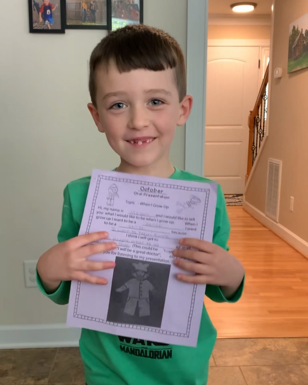 Mason Moore, grinning with a missing front tooth, holding his kindergarten 'When I Grow Up' presentation
