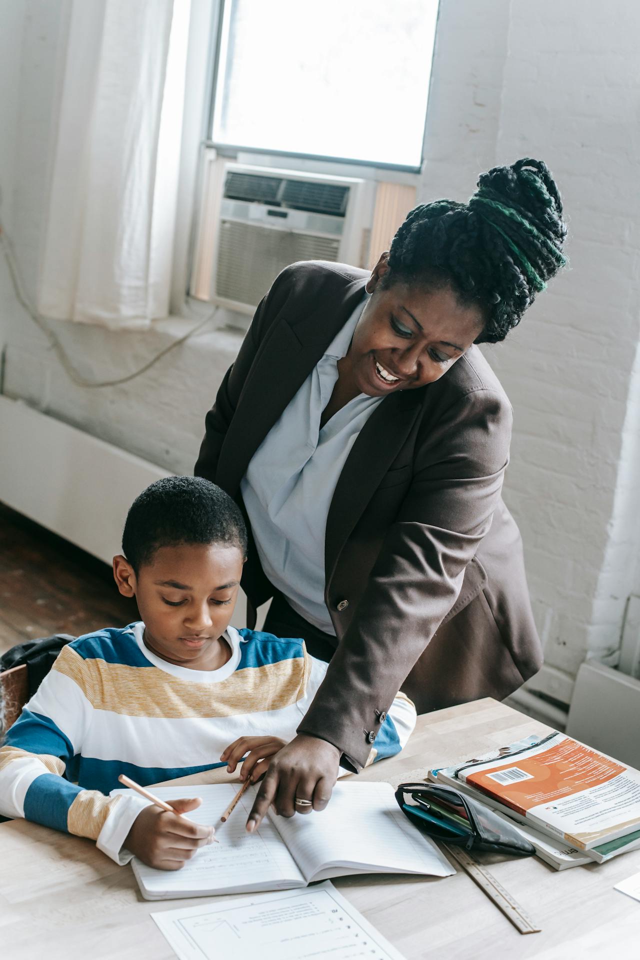 Teacher helping a child with reading at a desk
